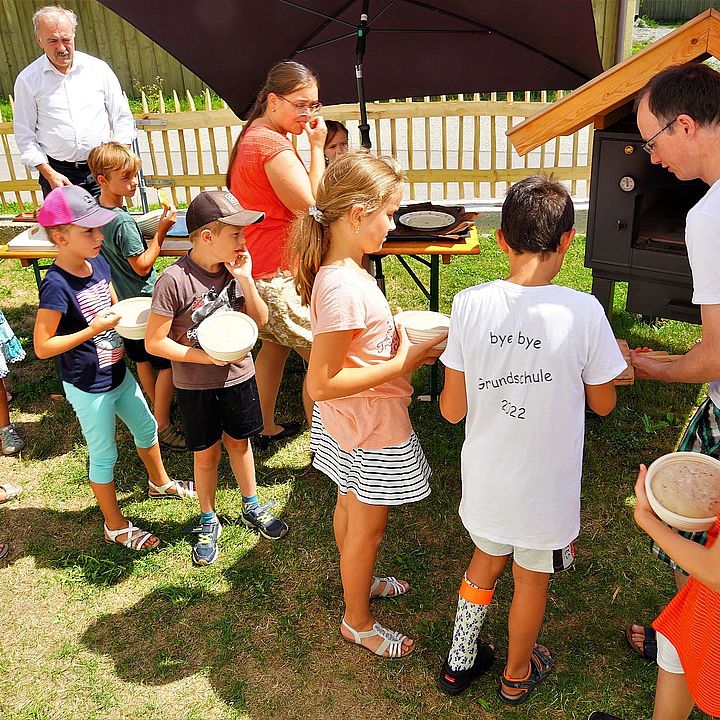 Kinder stehen Schlange, um ihren Brotteig backen zu lassen